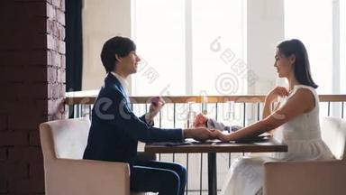 漂亮的年轻女子在餐馆里为求婚而兴奋，而她的男朋友则在聊天，然后戴上戒指
